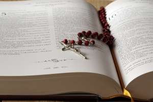 Rosary on Top of Opened Bible Book