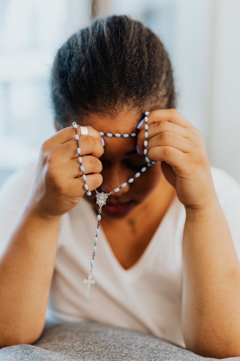 A focused image of a woman in prayer holding a rosary, conveying deep spirituality and faith.