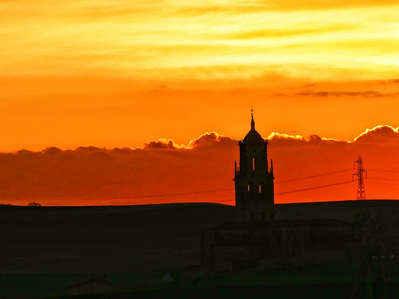 a building with a tower and a sunset in the background